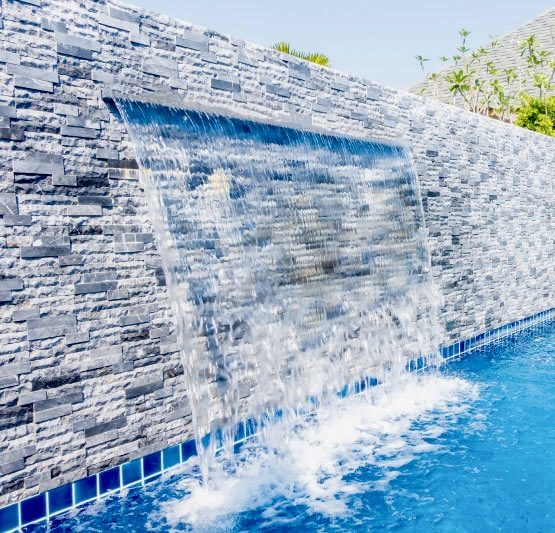 Stacked-stone water feature wall sheeting into a pool