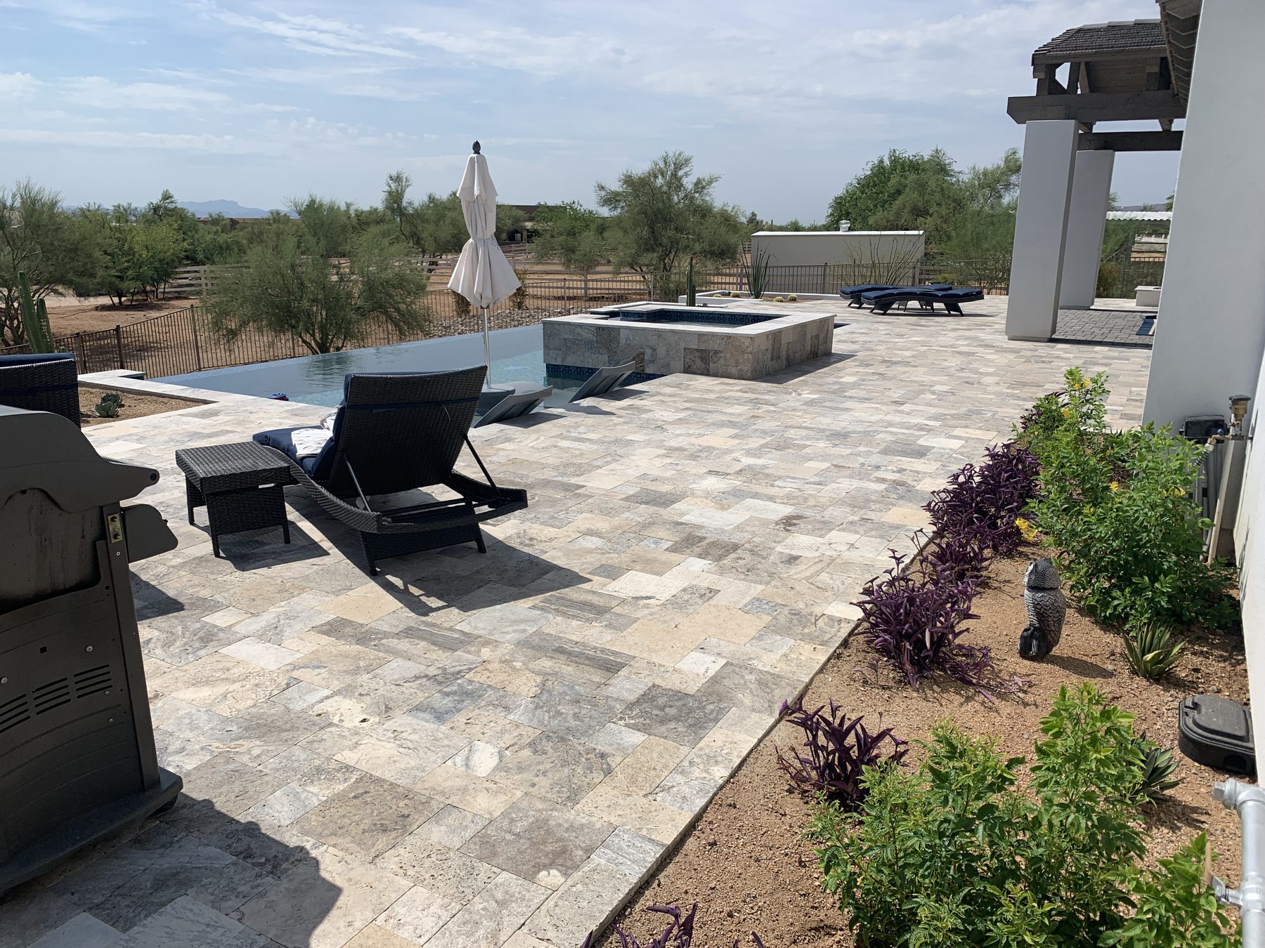 Travertine pool deck with raised spa and loungers — Standard Pools project