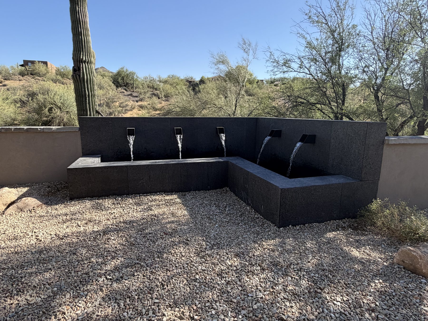 Dark stone water wall with four pouring scuppers — Standard Pools project