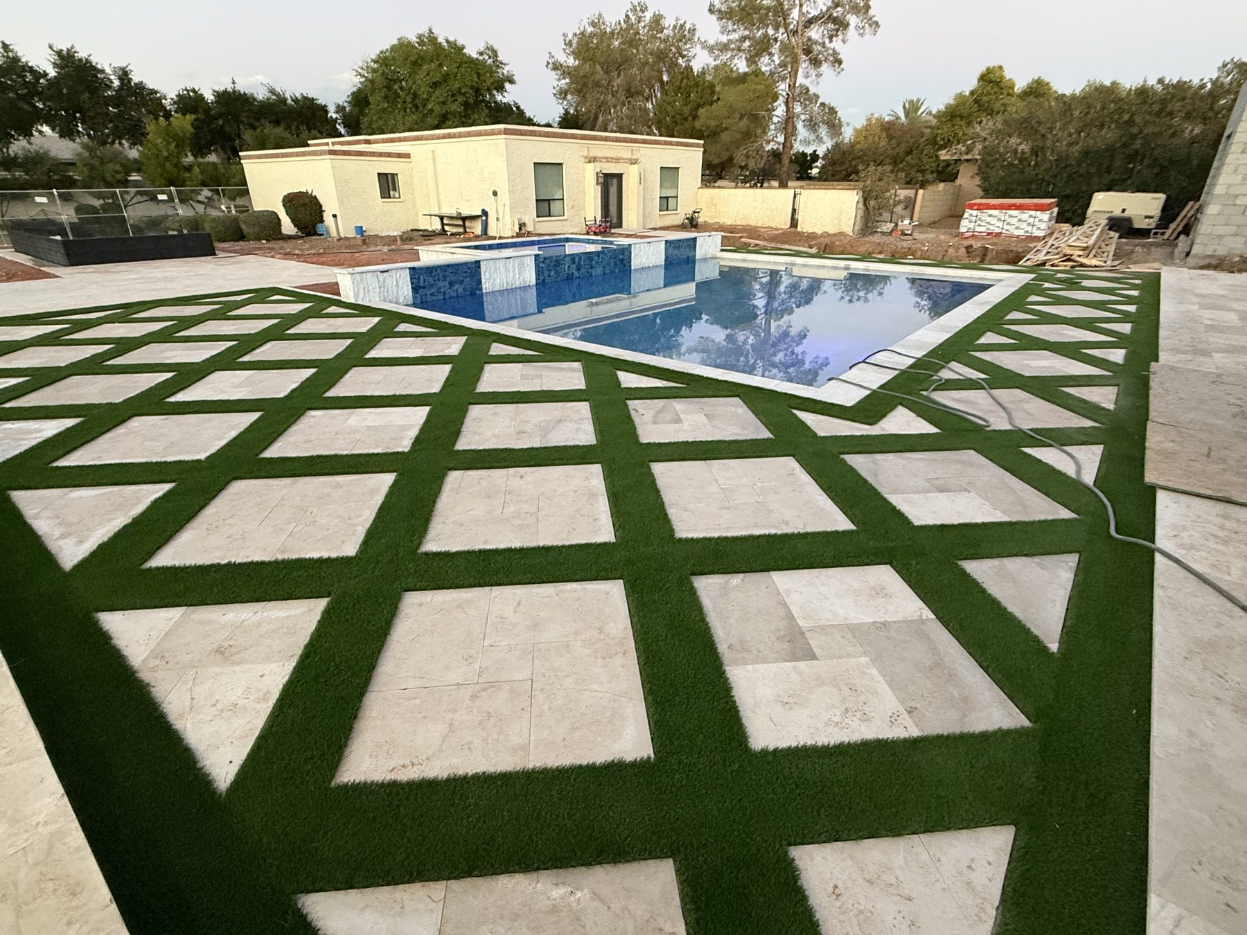 Diamond-pattern synthetic turf and paver decking around a pool — Standard Pools project